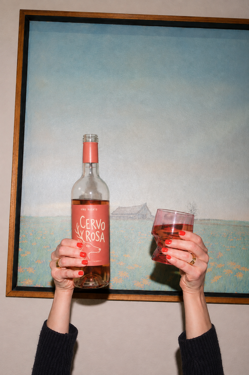 A bottle of Cervo being help up in one hand, and a glass in the other
